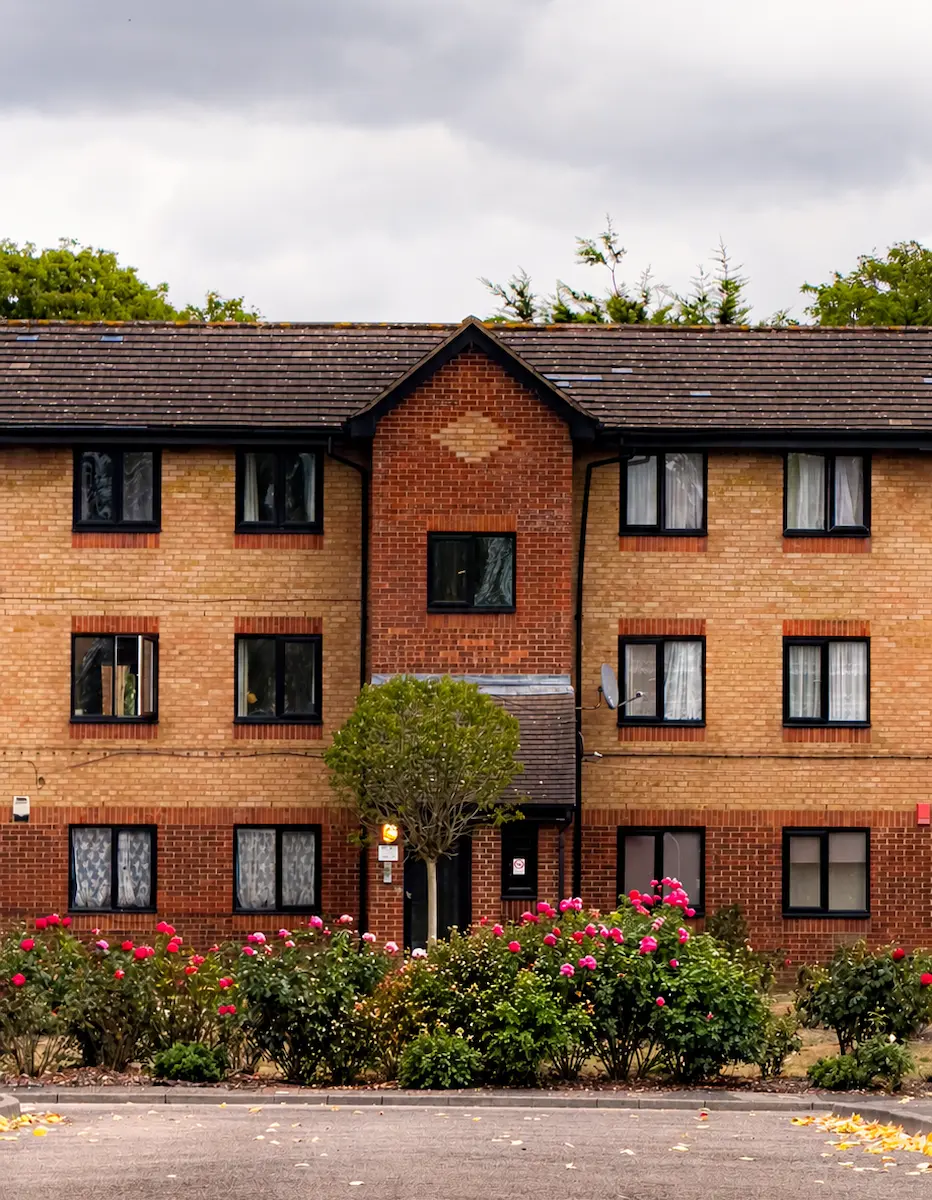Three-storey brick residential building with central entrance, landscaped frontage and parking